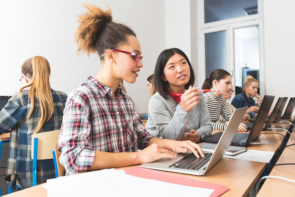 Group of female students coding on laptops in a computer lab